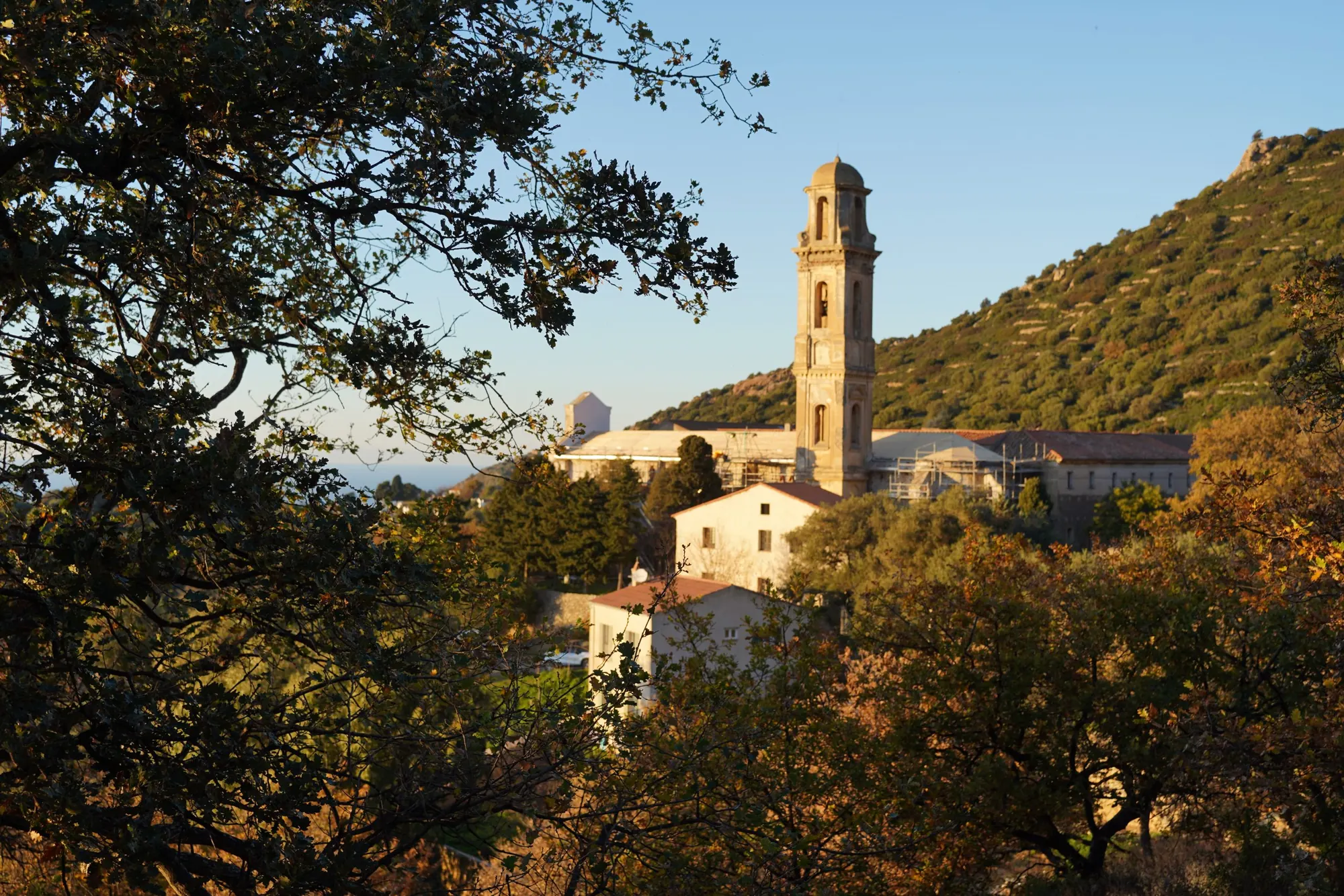 Village corse et clocher au coucher du soleil, montagnes en arrière-plan